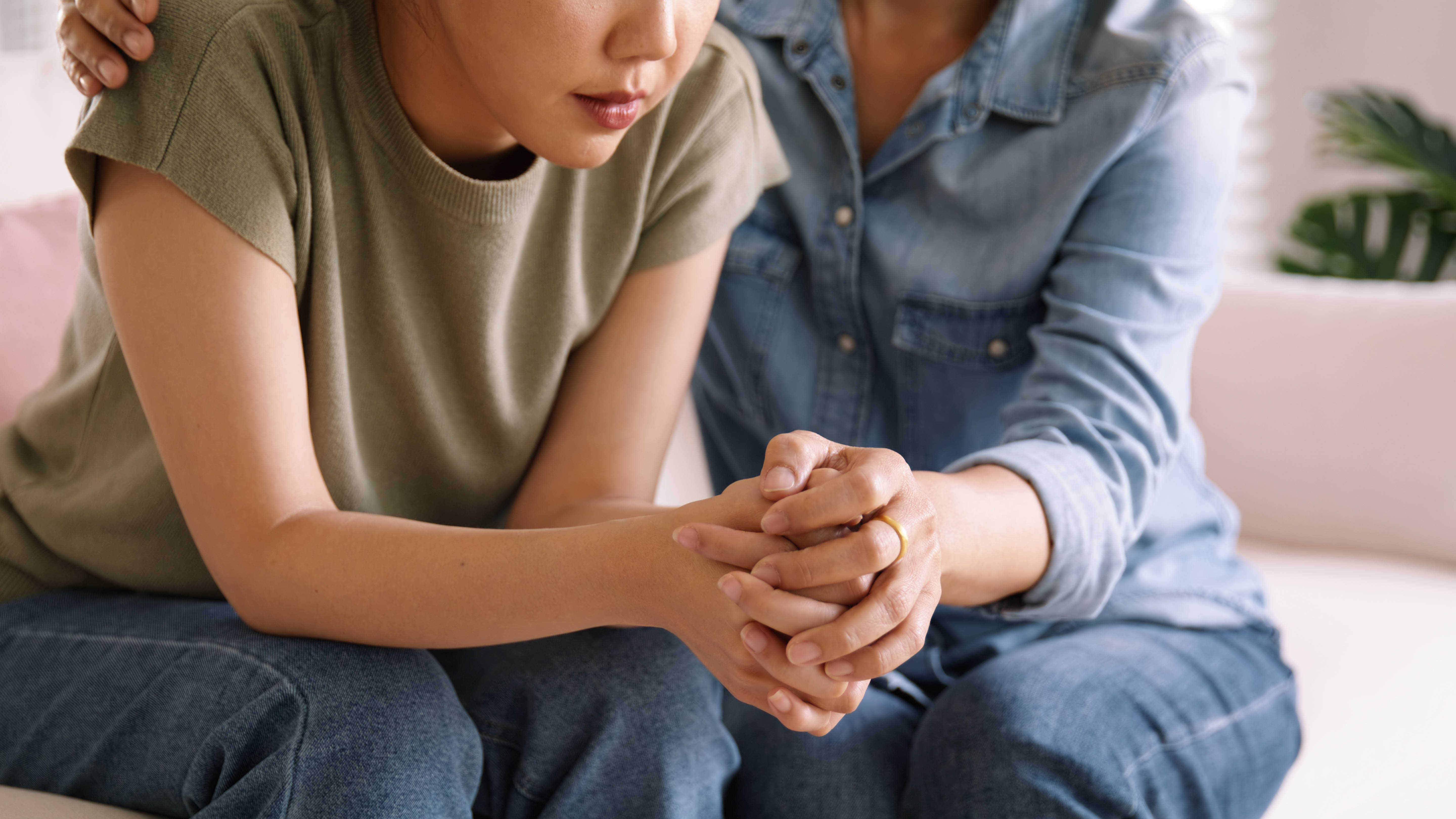 Young woman getting comforted as she struggles with grief